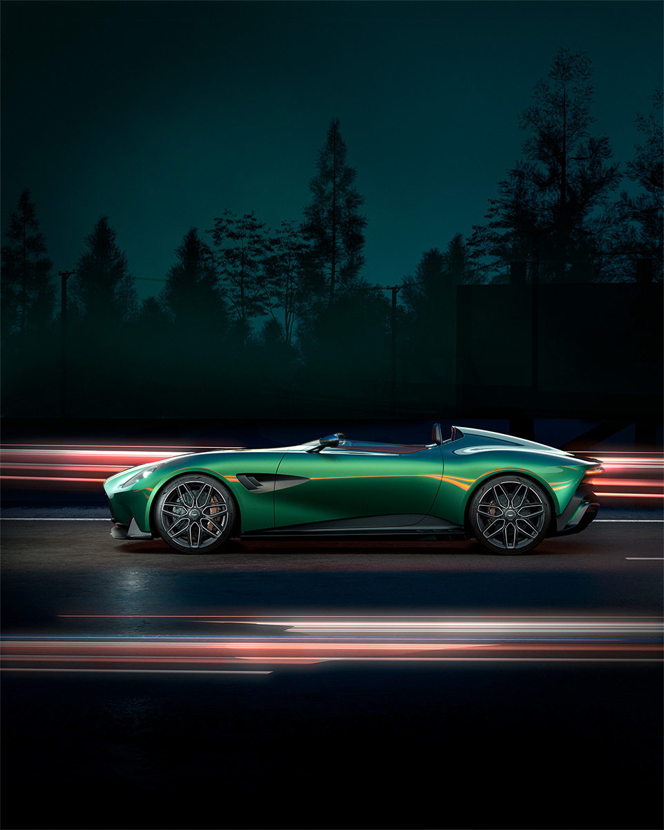 Side view of green Aston Martin driving down a road